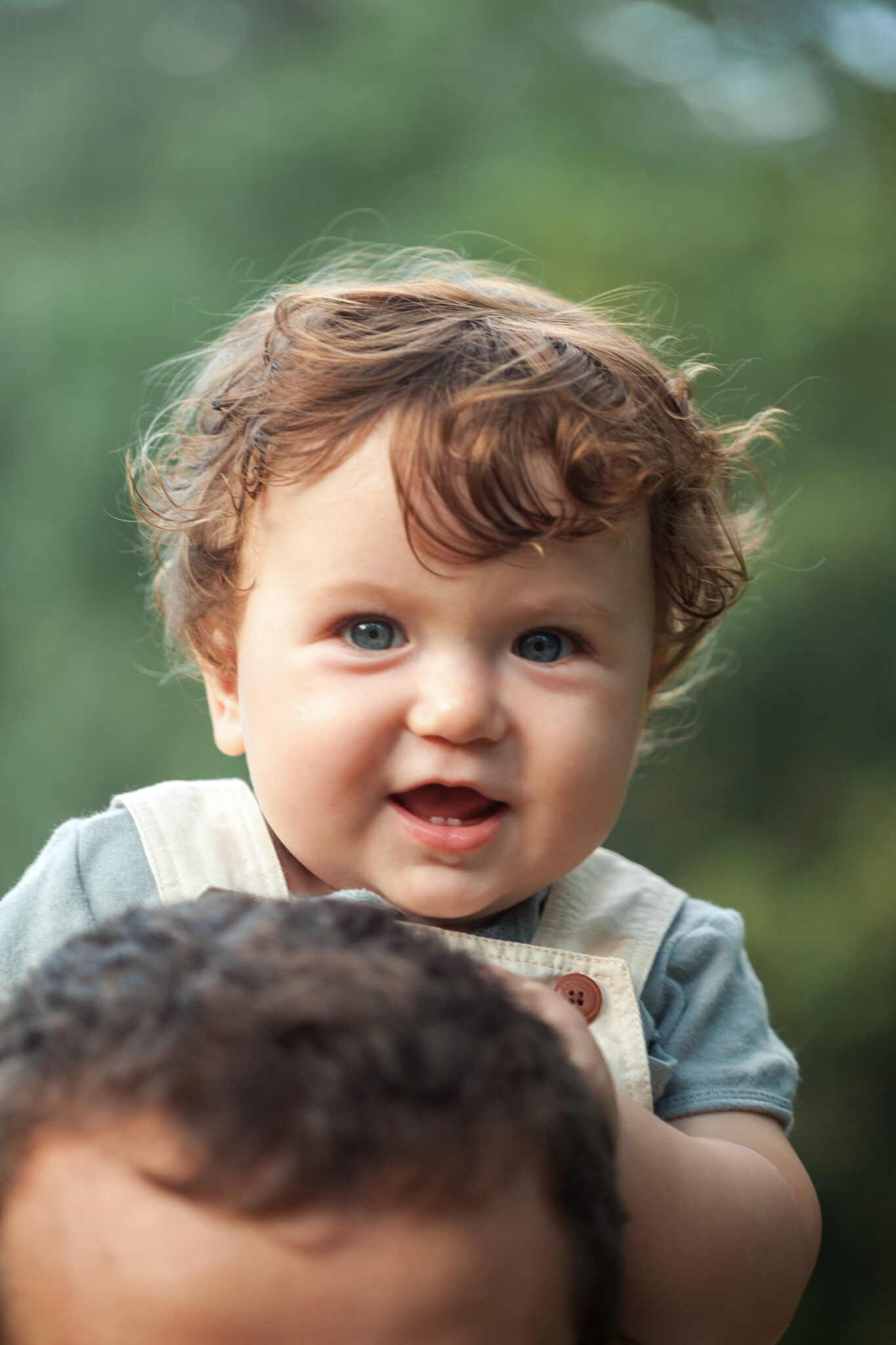 Home young beautiful father and little toddler son against green trees